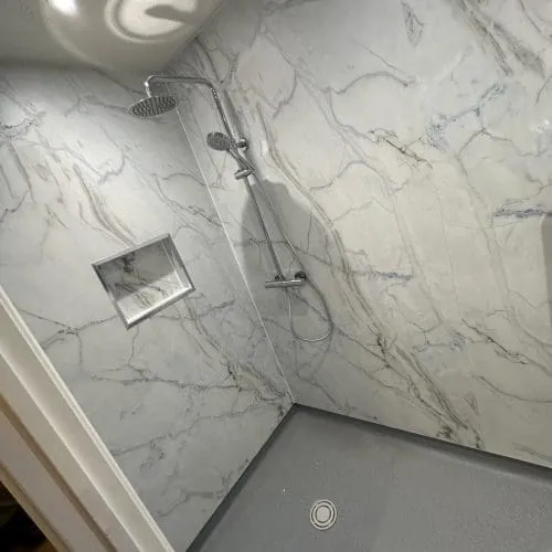 A wet room, with shower, and a recess in the wall for storage.