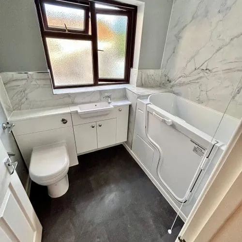 A bathroom with sink, toilet, and a walk in bathtub.